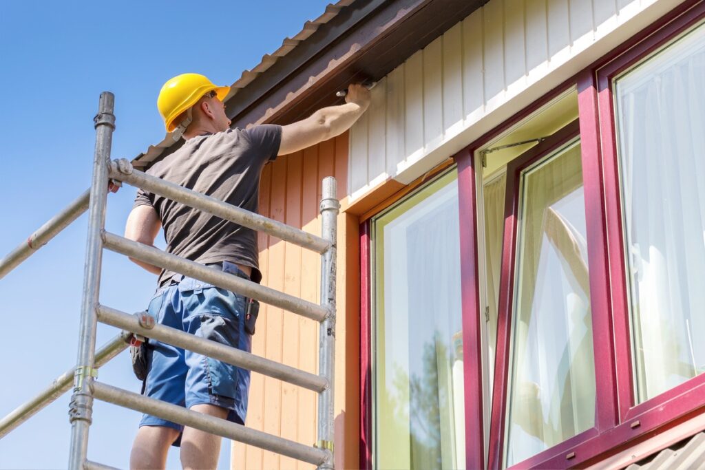 a man on a ladder painting his home